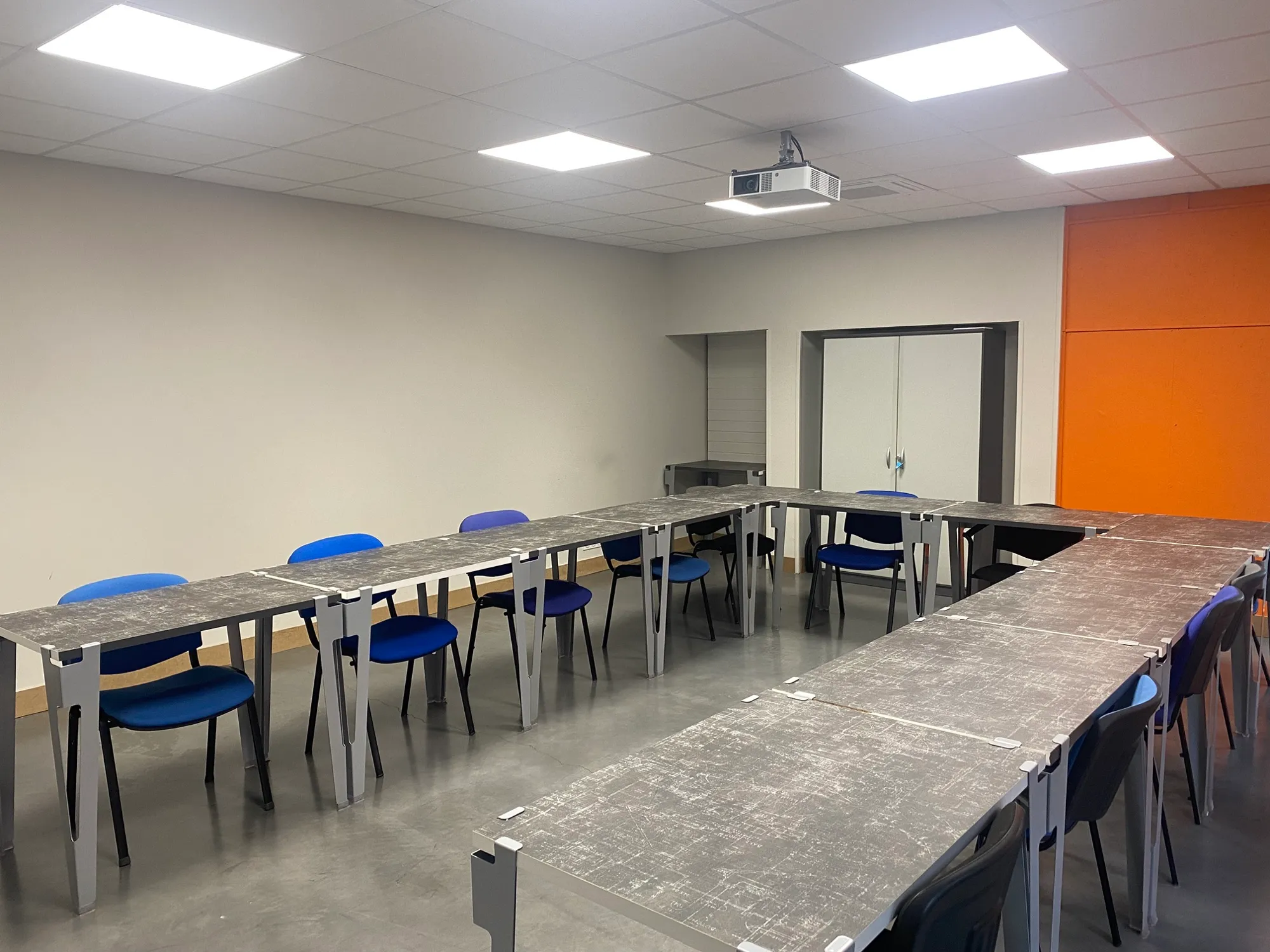 Salle de formation du tiers-lieu Les 5 Éléments, tables en U face au vidéoprojecteur